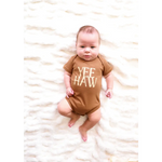 Baby in a brown organic cotton bodysuit with YEE HAW for little cowboys and cowgirls