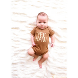 Baby in a brown organic cotton bodysuit with YEE HAW for little cowboys and cowgirls
