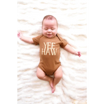 Baby in a brown organic cotton bodysuit with YEE HAW text on soft fabric