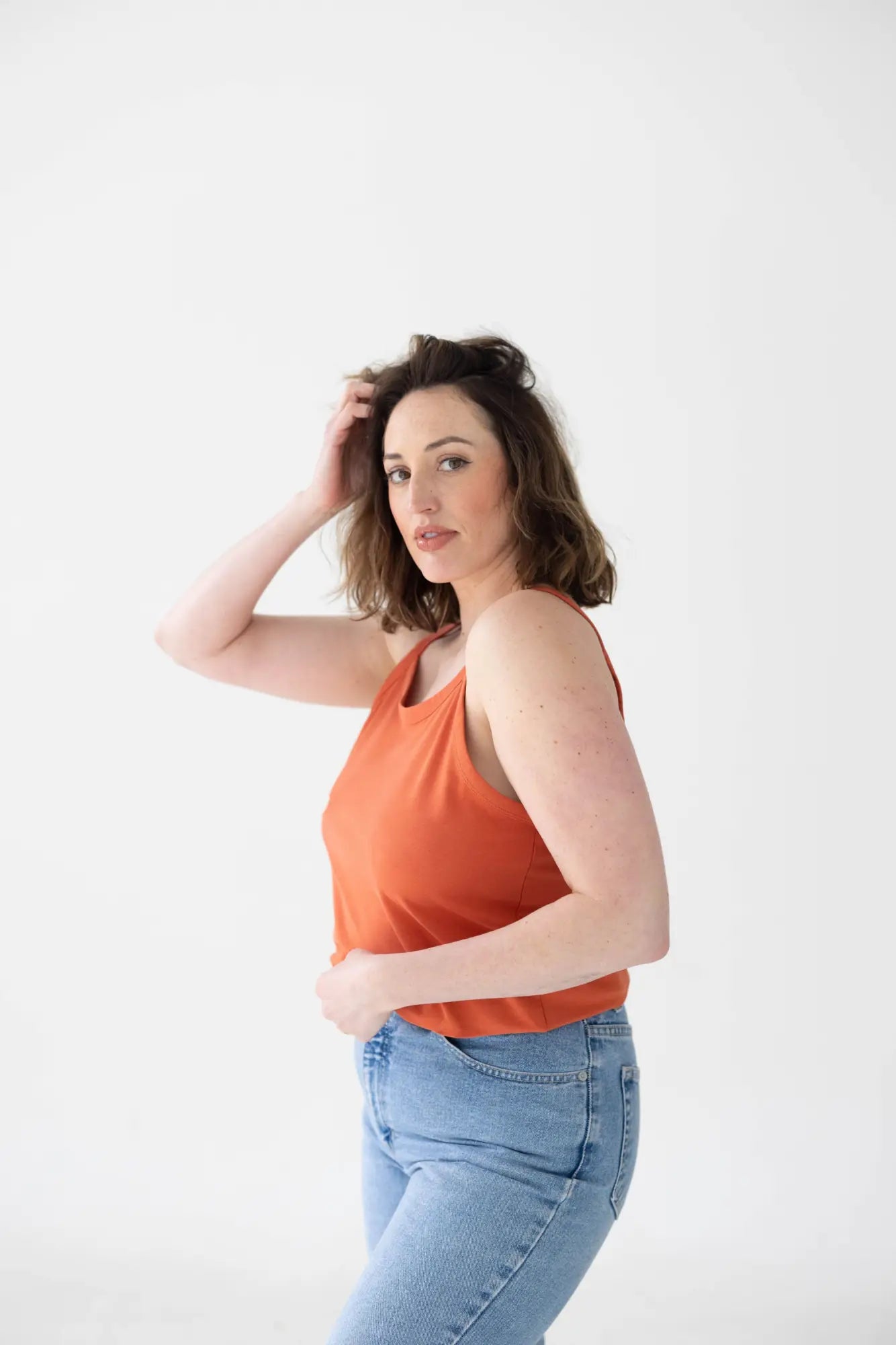 Person in coral tank and high-waisted jeans from Core Basics Mom Crop collection.