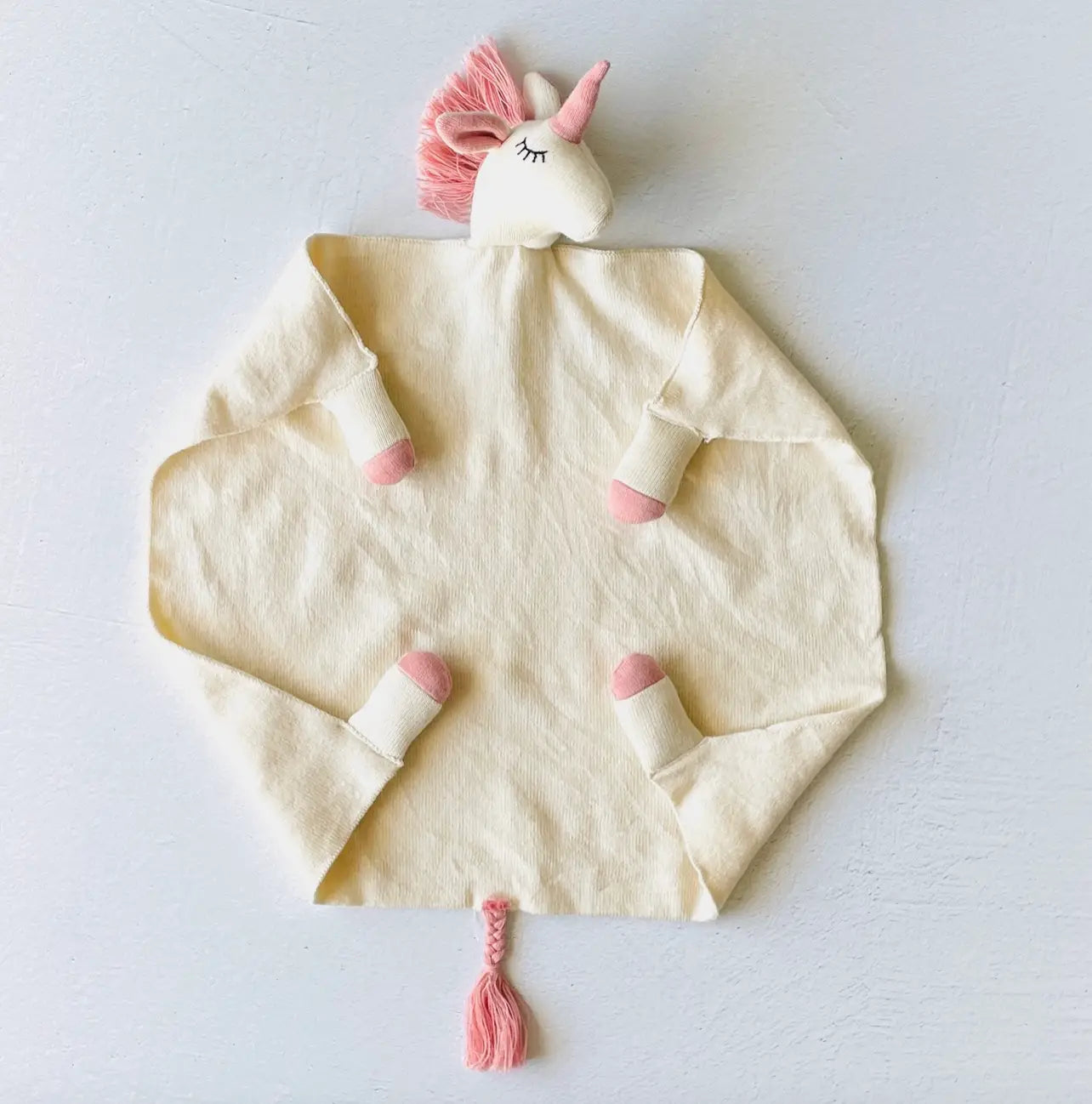 White unicorn security blanket in organic cotton fine knit with pink accents and braided tail.