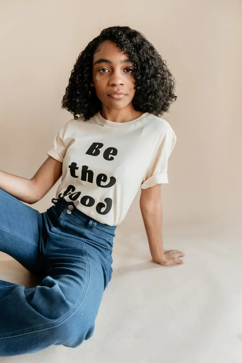 Person in a Be the Good t-shirt and jeans, rocking empowered women empower vibes.