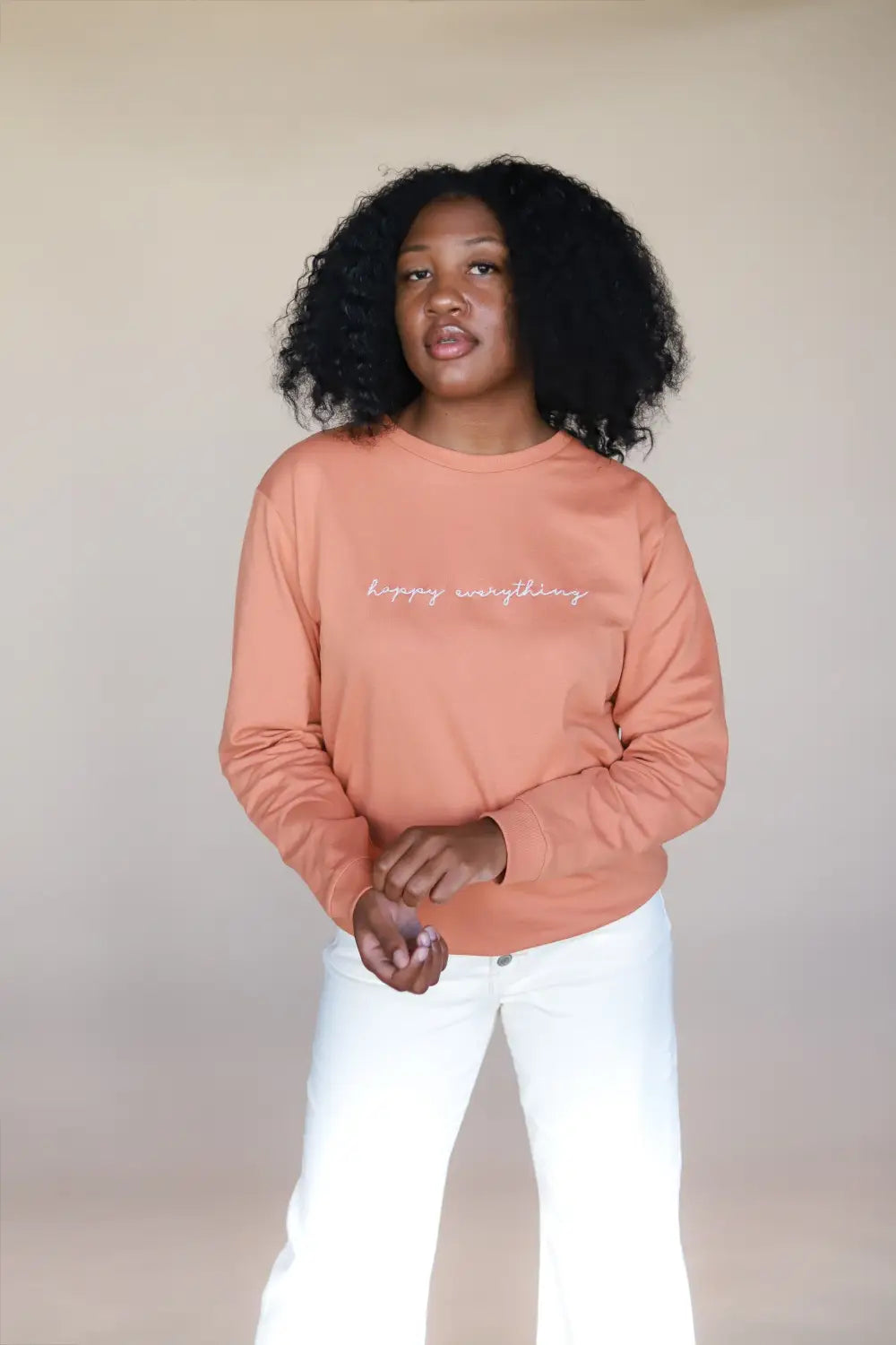 Peach sweatshirt with white text paired with white pants at Peace Signs Camp collection.