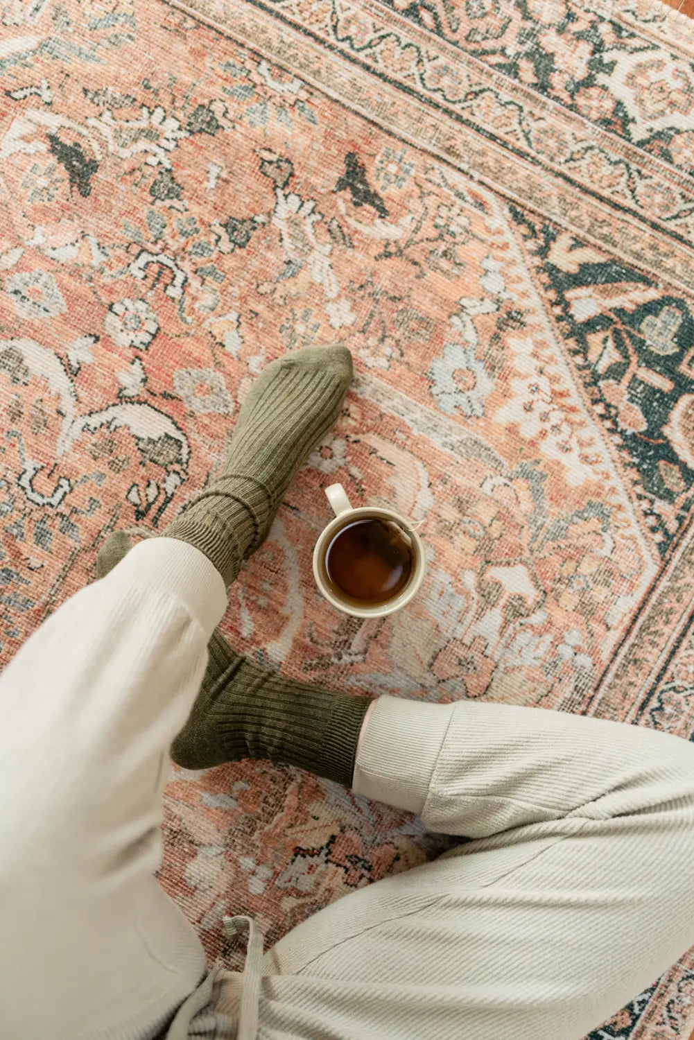 Cozy coffee on a Persian rug with cute socks and fun toddler baby accessories.