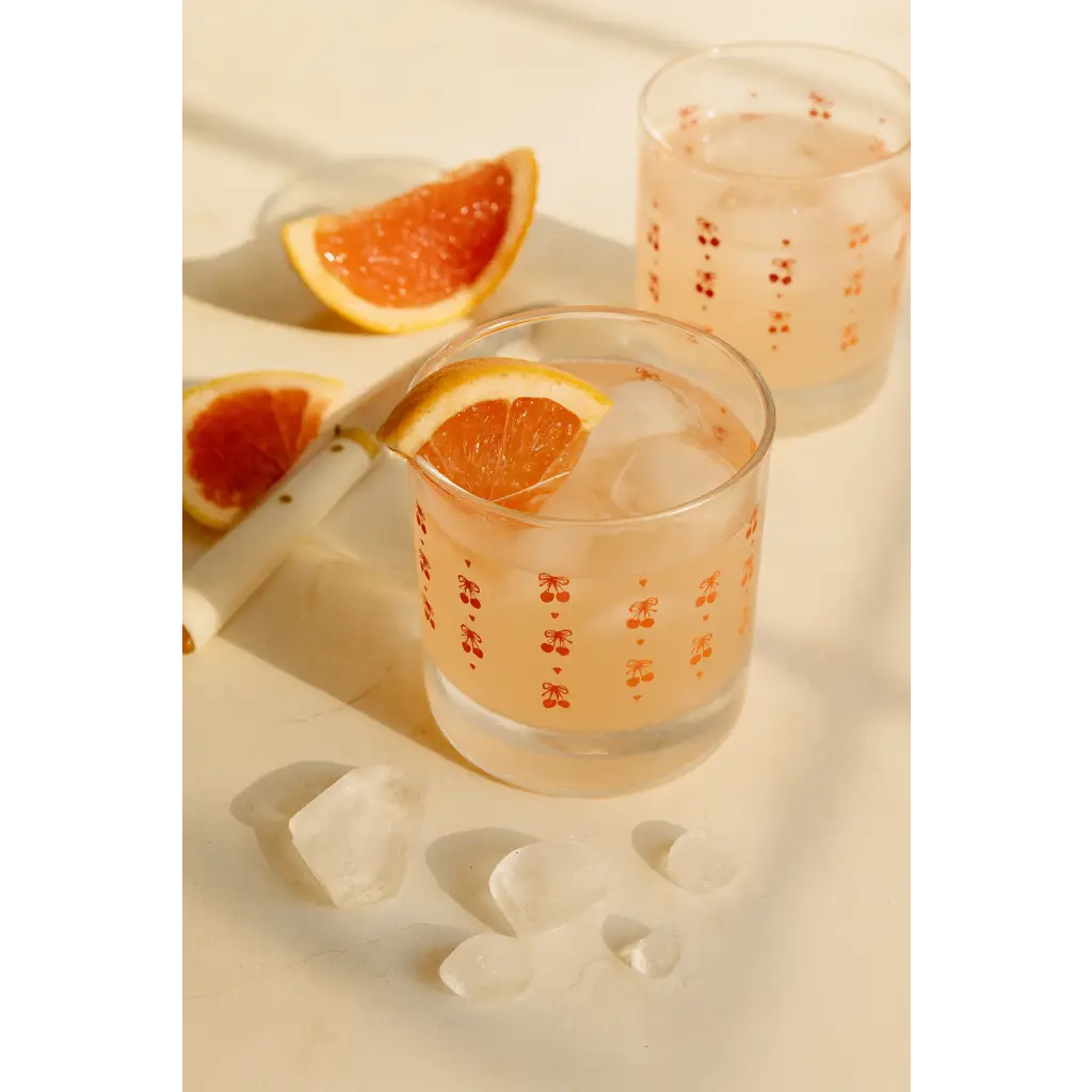 Clear glass tumbler with cherry decals, orange garnish bar cart accessory