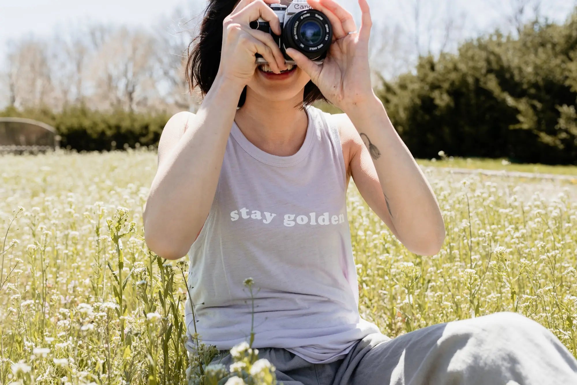 Woman holding camera in stylish women’s clothes for capturing polished prints.