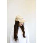 Beige embroidered baseball hat styled with a white sweater and long dark hair