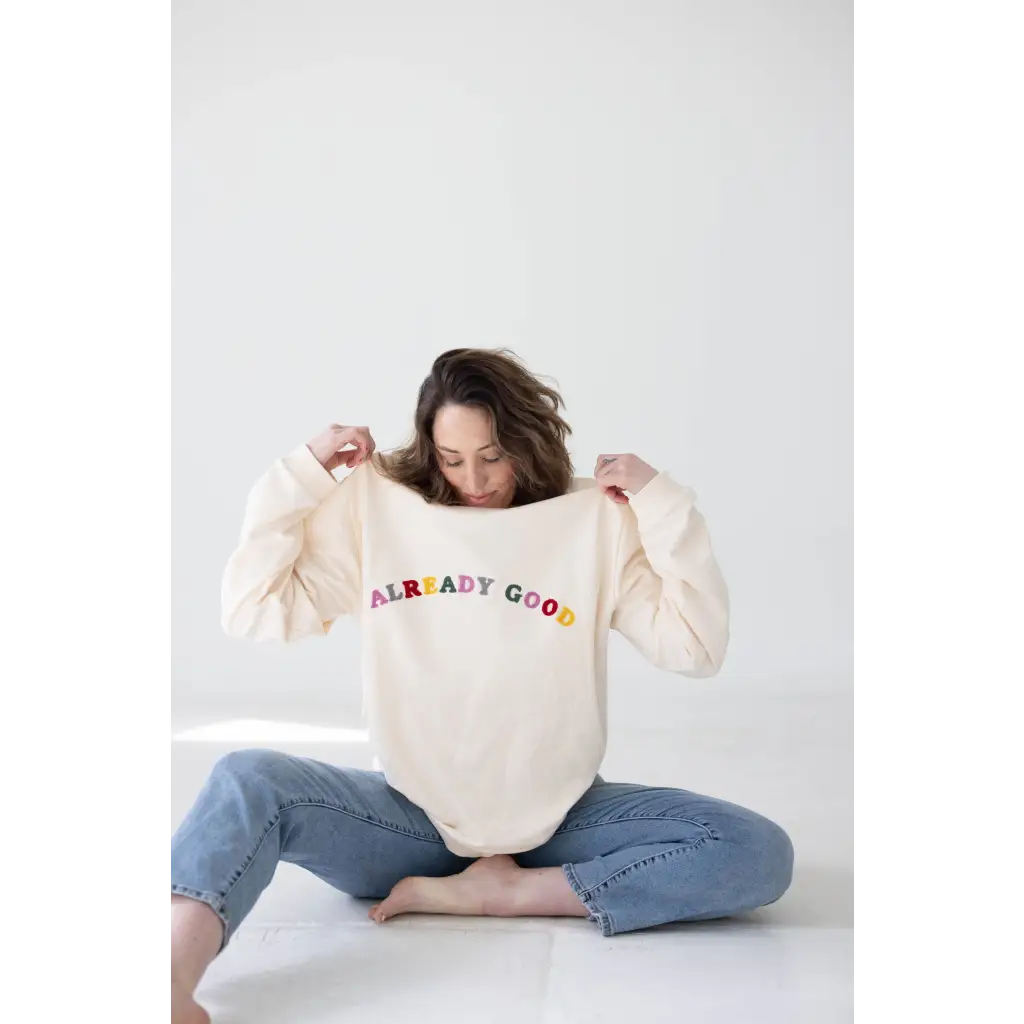 Cream-colored sweatshirt with colorful ALREADY GOOD text for a comfy organic cotton look