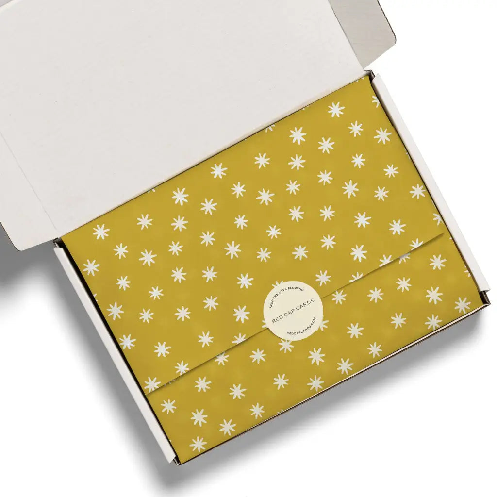 Mustard yellow Asterisk tissue paper with white starburst pattern and silver logo, perfect for stylish womens clothes