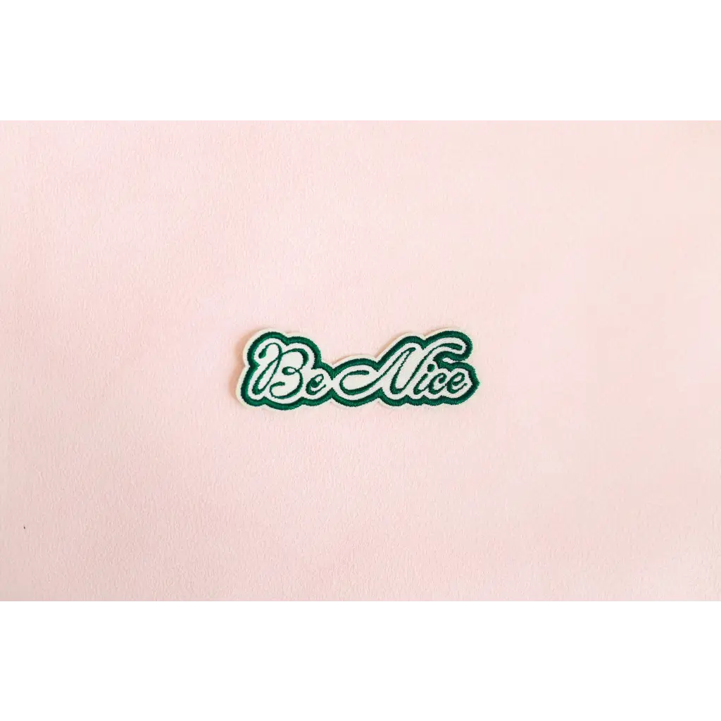 Be Nice iron-on patch with green cursive lettering and white outline for spreading kindness