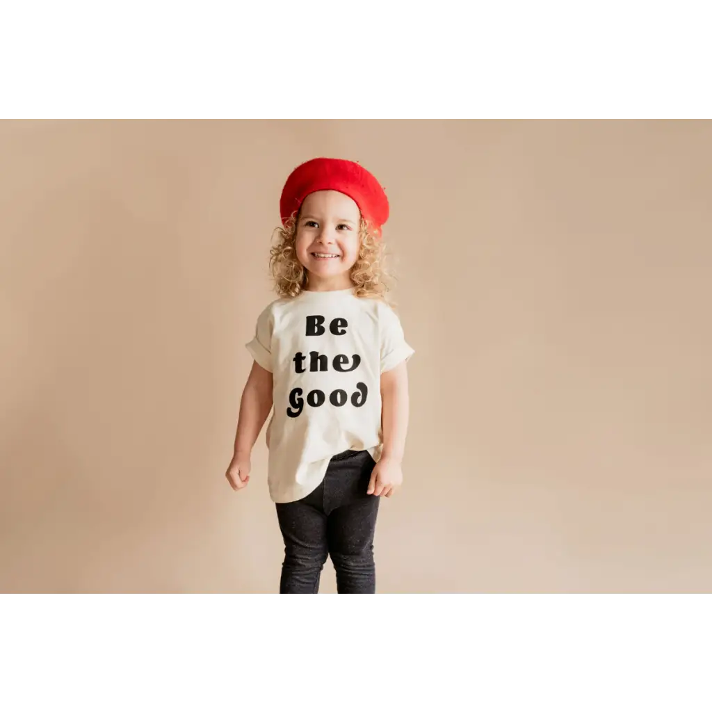 Child in a red beret rocks a Be the Good Organic Cotton Graphic T-shirt by Polished Prints