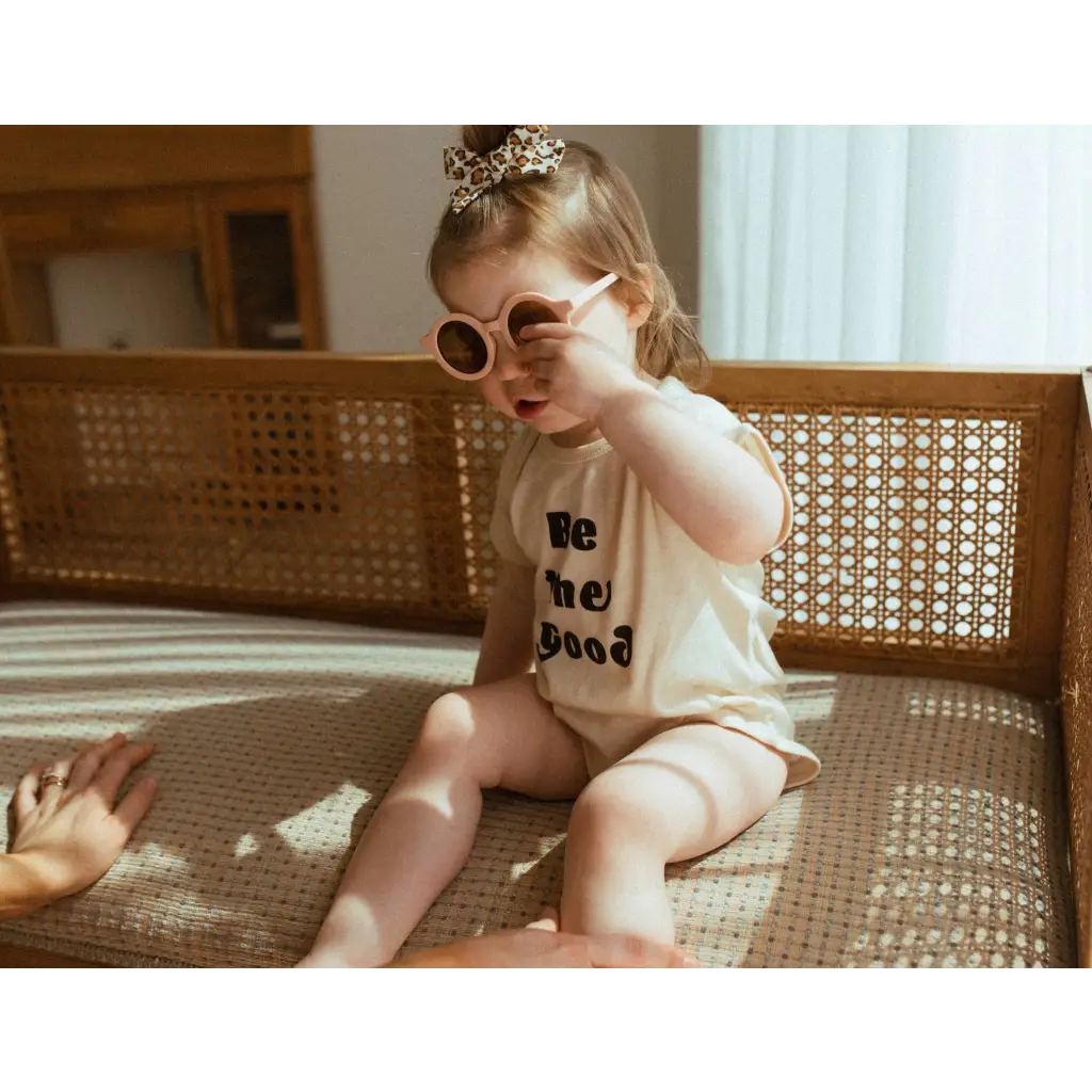 Toddler in pink sunglasses on bench wearing Good Organic Cotton Baby Bodysuit
