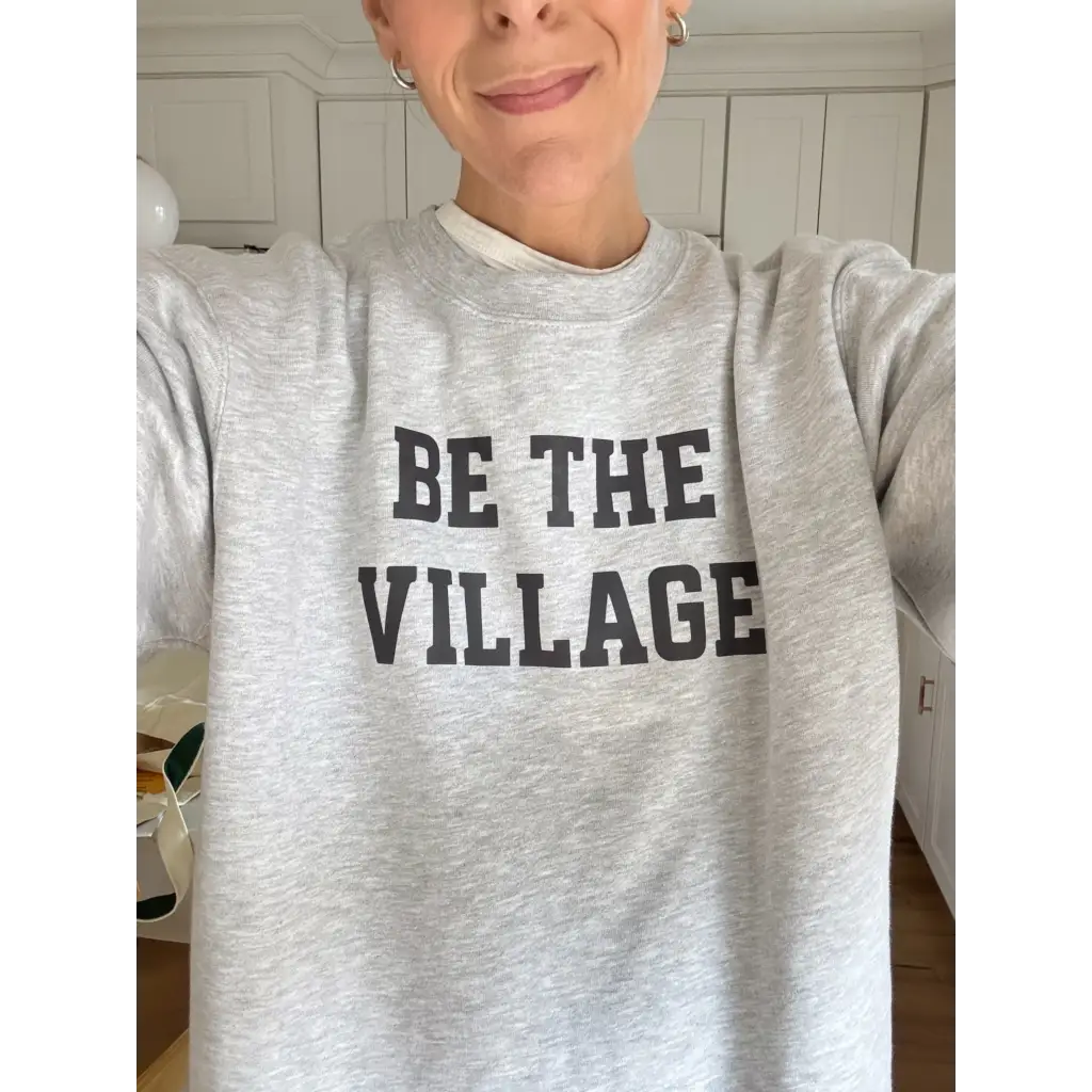 Heather gray Be the Village adult unisex pullover with bold black text