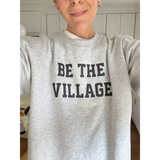 Heather gray Be the Village adult unisex pullover with bold black text