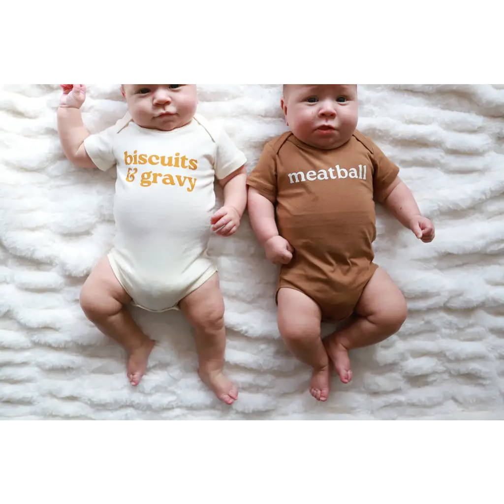 Two babies in adorable organic cotton gender neutral onesies featuring fun food themes