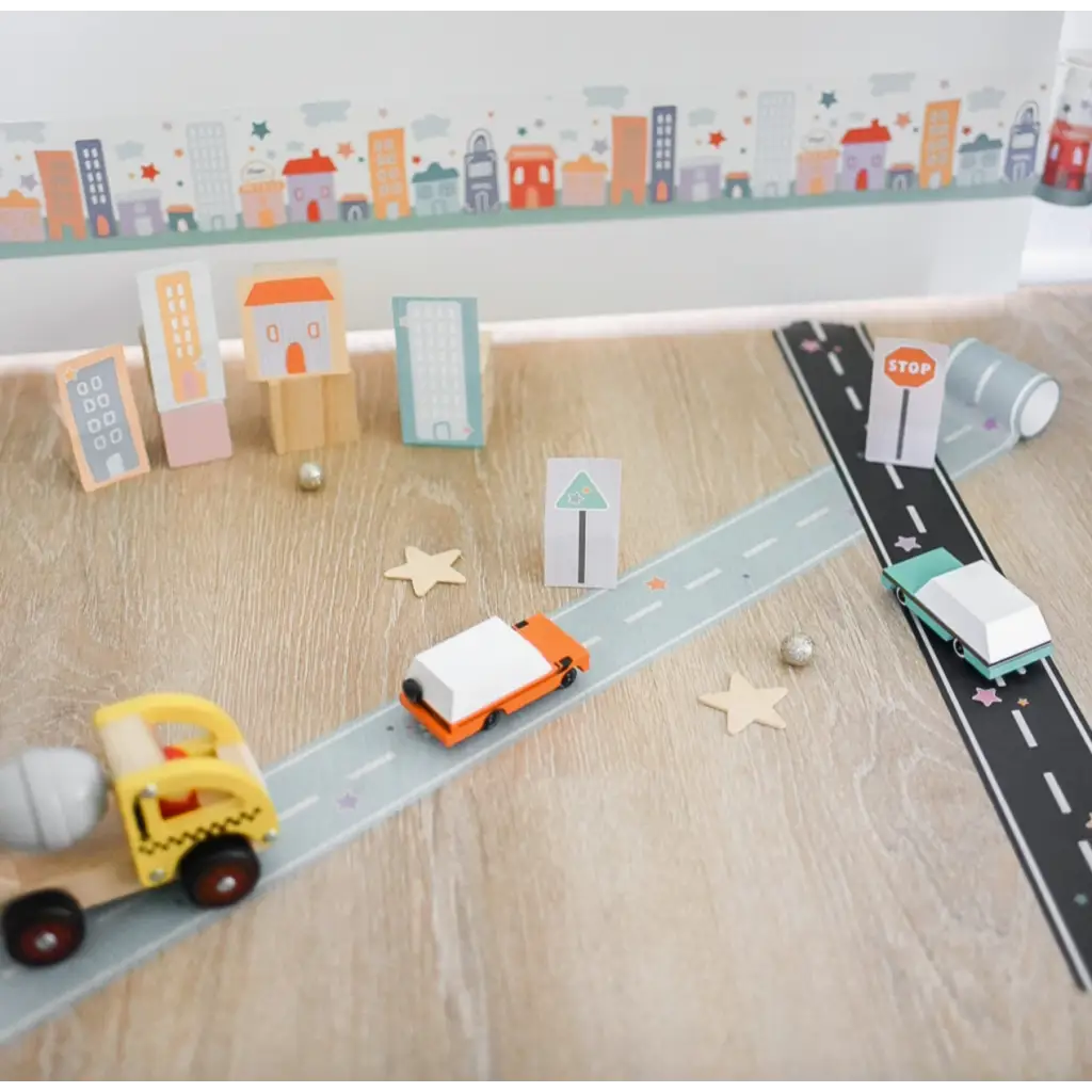 Toy road setup with miniature vehicles and buildings using Black Play Road Tape