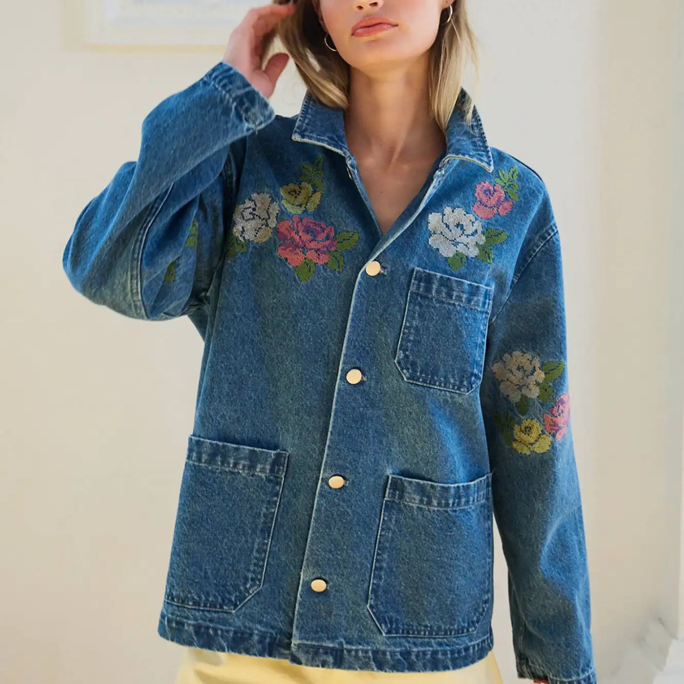 Blue denim jacket with colorful floral embroidery on the chest and sleeves.