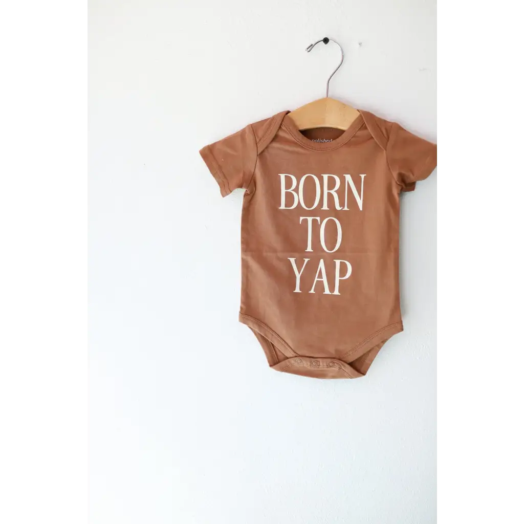 Brown organic cotton baby onesie on a hanger from Born to Yap collection