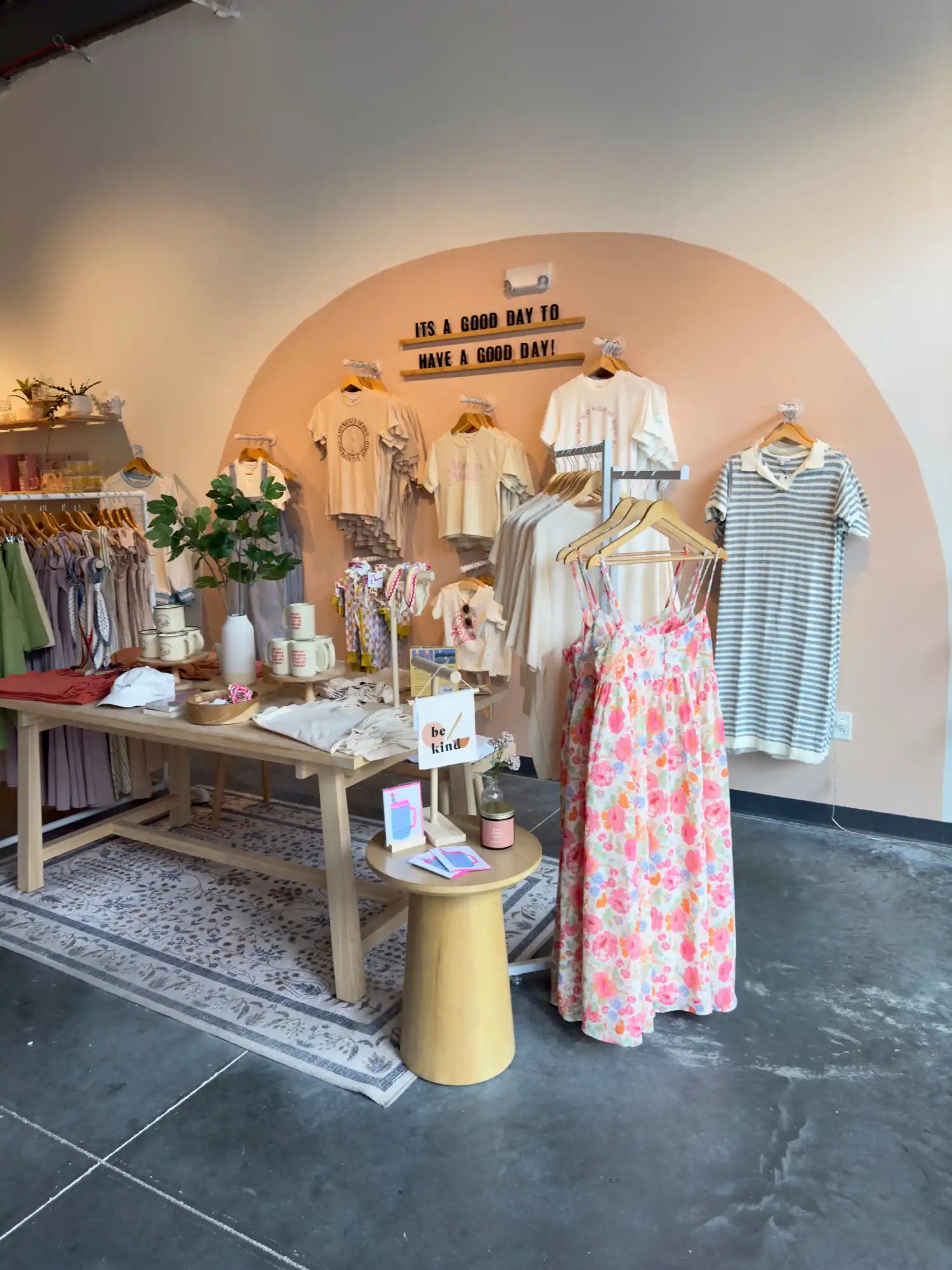 Boutique clothing display featuring summer dresses and accessories arranged under an arched alcove.