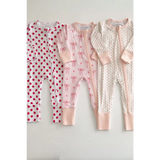 Three pink and white bamboo baby sleepers with polka dots, bows, flowers