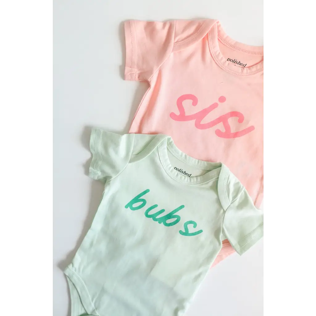 Two baby onesies in pink and mint green with polished prints, made from organic cotton