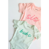 Two baby onesies in pink and mint green with polished prints, made from organic cotton