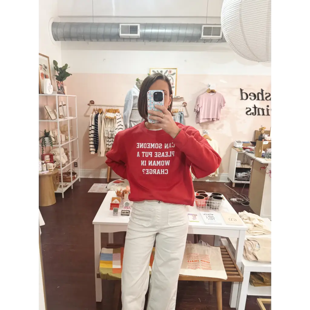 Red long-sleeved adult unisex pullover with Can someone put a woman in charge text