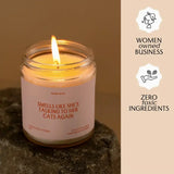 Lit candle in a glass jar with a funny cat label, Rose + Patchouli scent, small batch quality