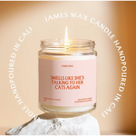 Lit candle in a jar with a funny cat label, featuring Rose + Patchouli, made in small batches