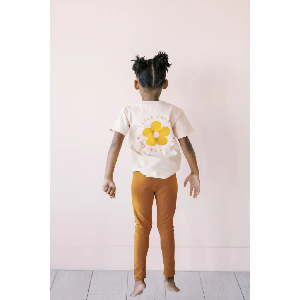 Child in white flower tee and orange pants with Good Vibes Flexible Lightweight Leggings