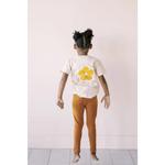 Child in white flower tee and orange pants with Good Vibes Flexible Lightweight Leggings