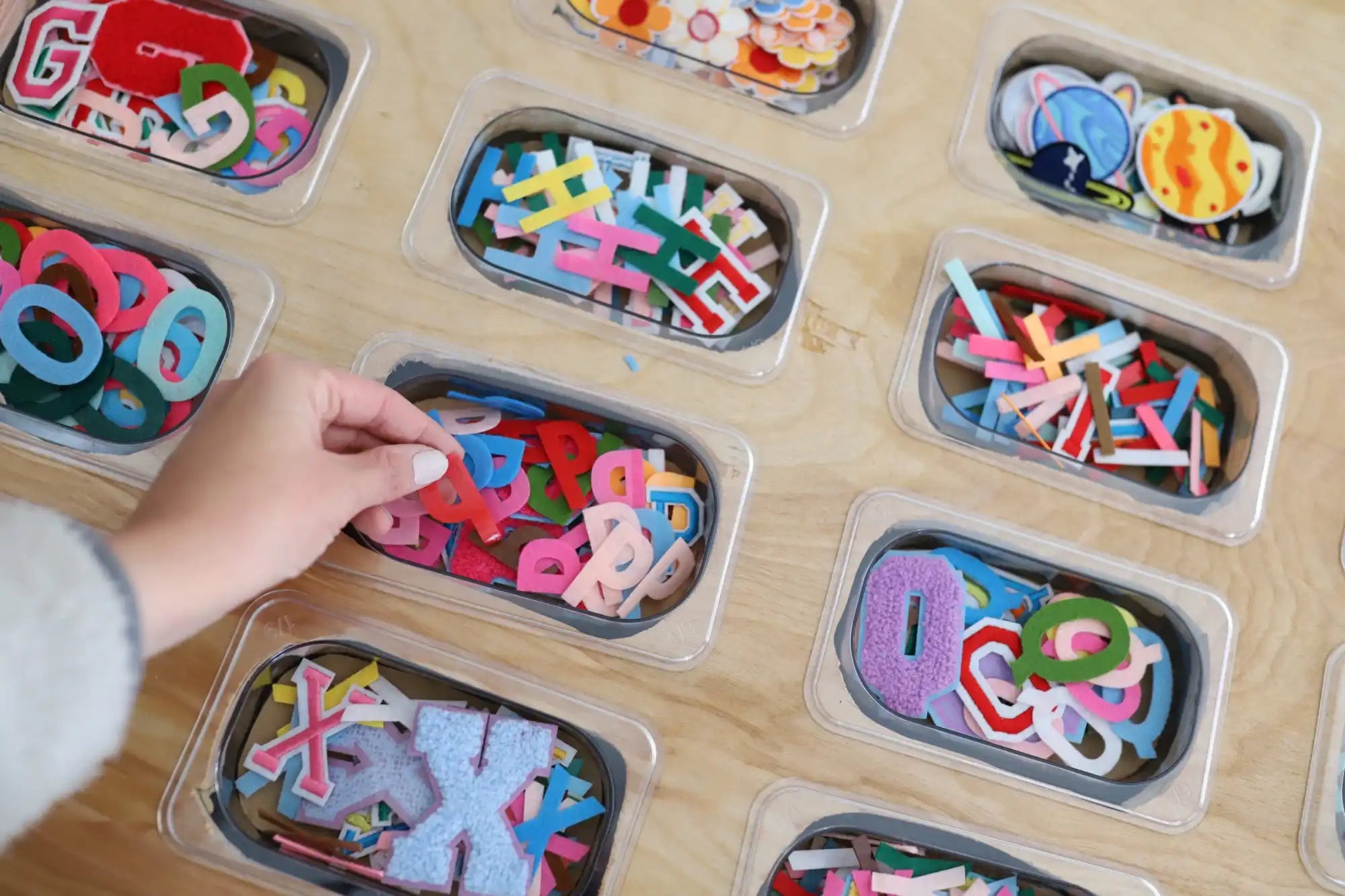 Colorful magnetic letters and numbers organized in plastic storage containers.