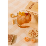 Iced cocktail in Cowboy Cocktail Glass with lemon peel and raspberry, perfect for peace signs camp vibes