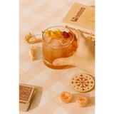 Iced cocktail in Cowboy Cocktail Glass with lemon peel and raspberry, perfect for peace signs camp vibes