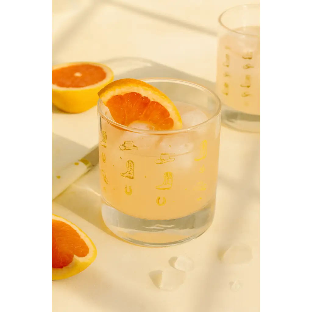 Glass of grapefruit juice with ice and a grapefruit slice in a Cowboy Cocktail Glass