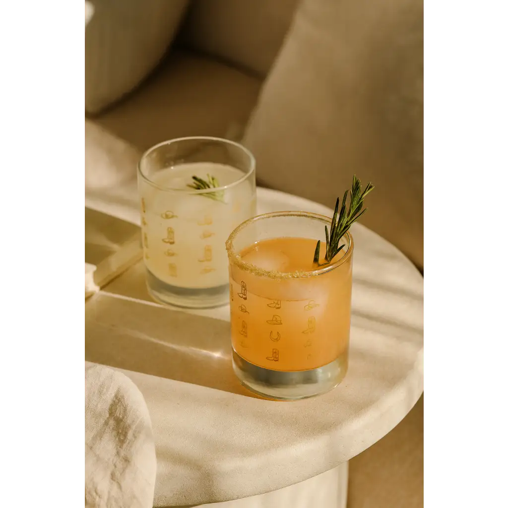 Two refreshing cocktails in Cowboy Cocktail Glasses with rosemary, perfect for peace signs camp