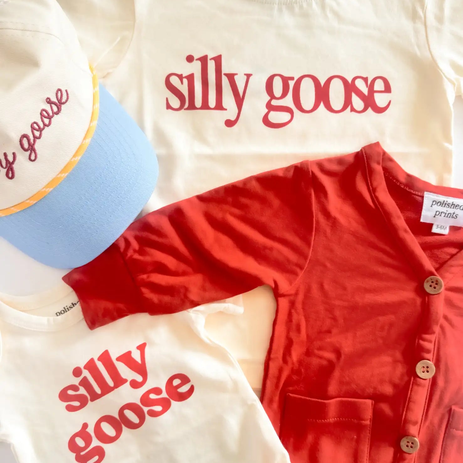 Cream-colored t-shirt with light blue ribbed collar and red ’silly goose’ lettering.