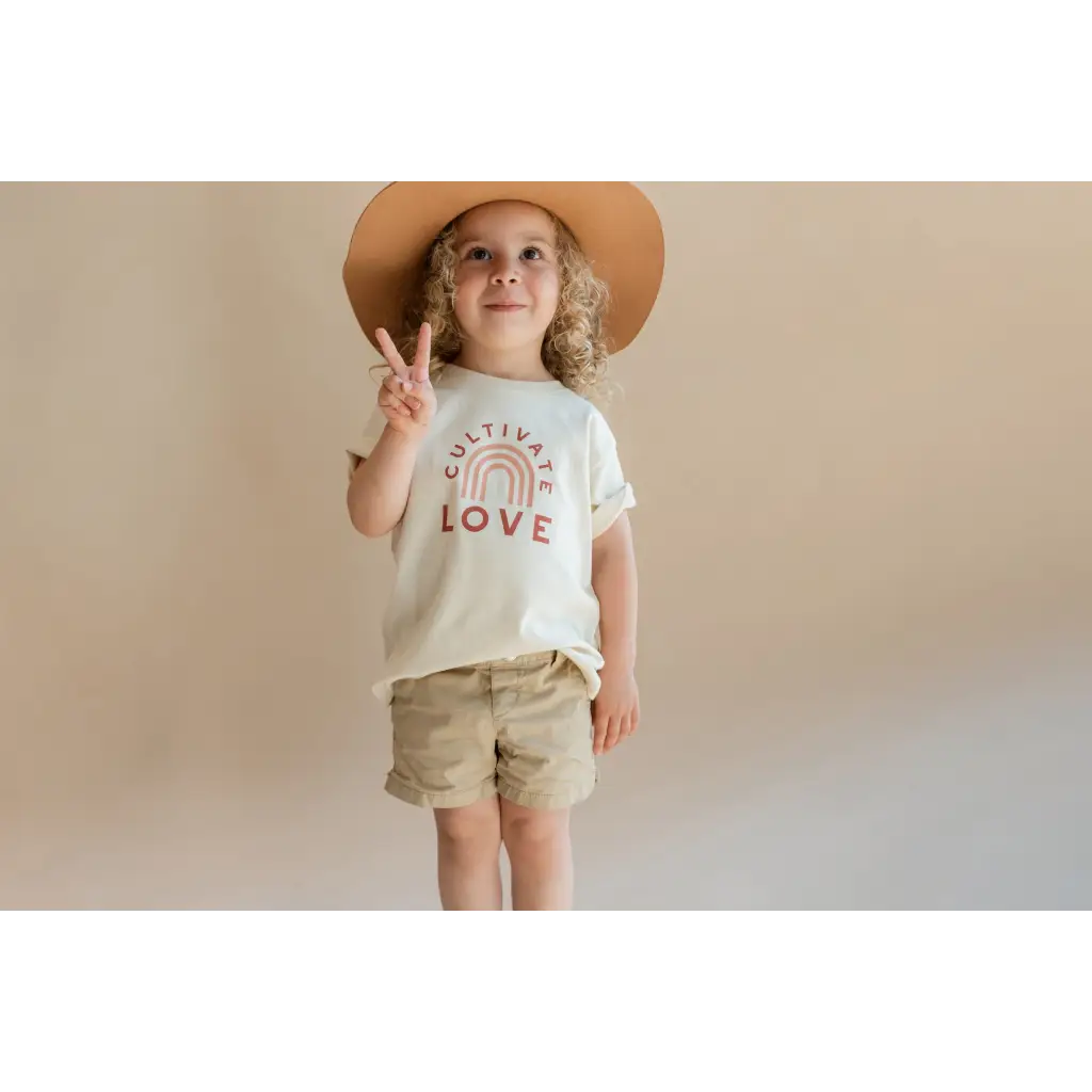 Child in a wide-brimmed hat and LOVE t-shirt promoting Cultivate Love Organic Cotton for kids