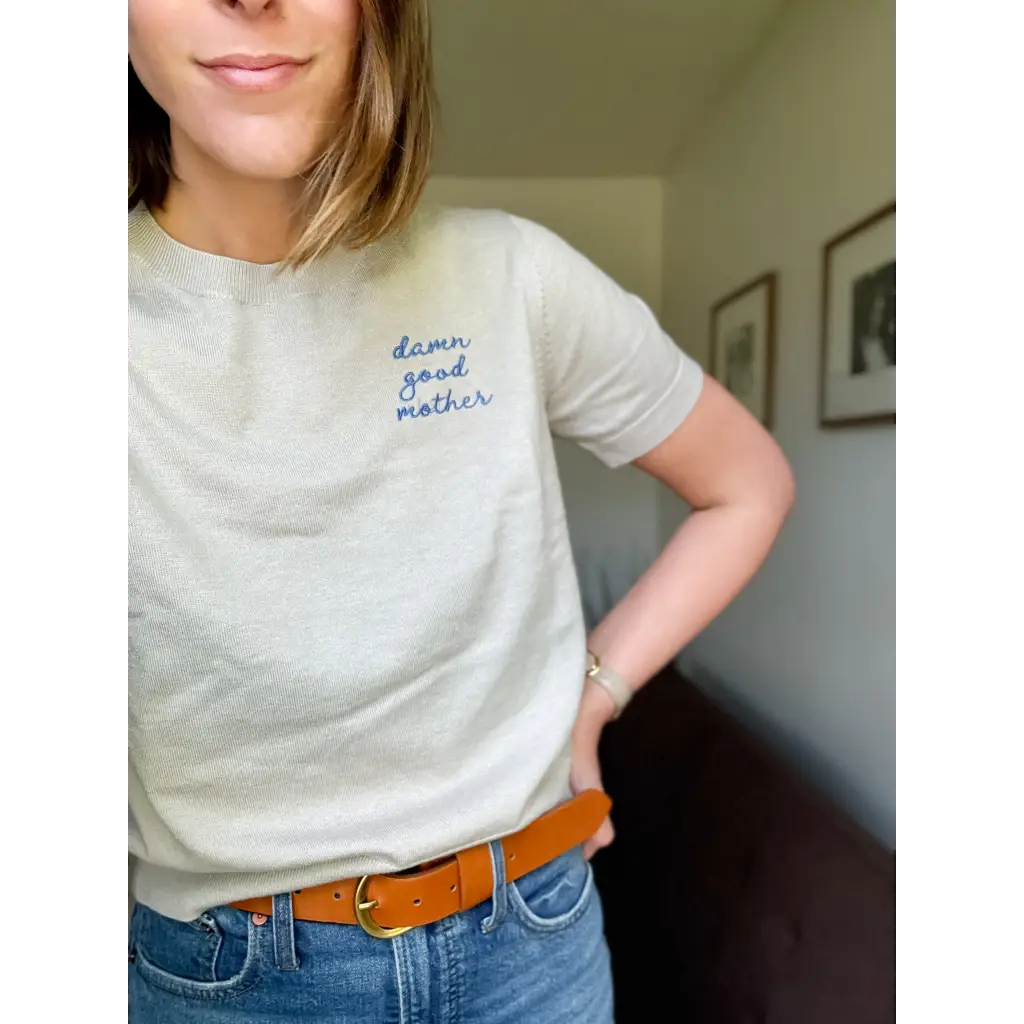 Woman wearing a beige T-shirt from the Damn Good Mother Sweater Tee collection