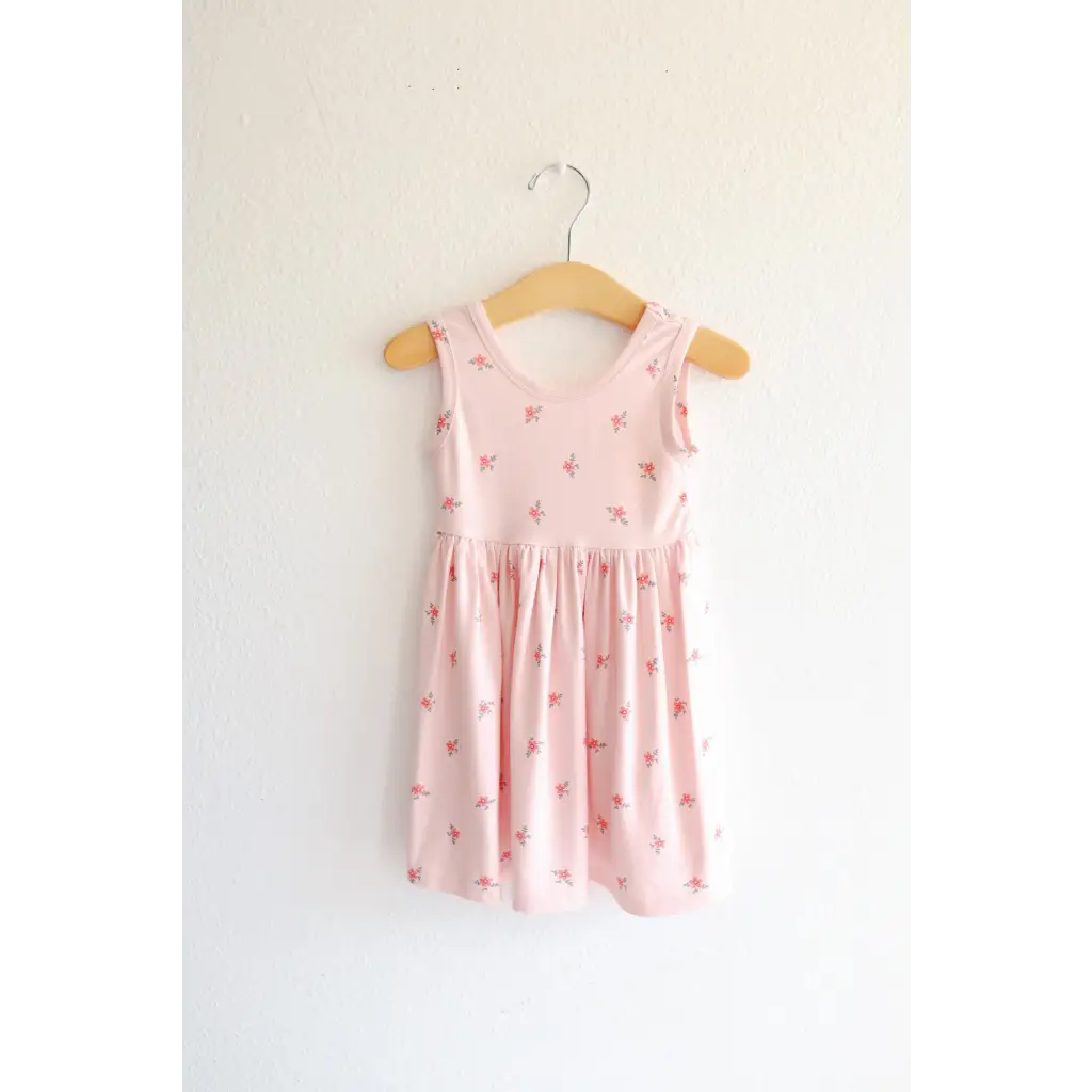 Pink Daisy Twirl Dress hanging on a wooden hanger with floral prints for a cute look