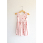 Pink Daisy Twirl Dress with floral prints hanging on a rustic wooden hanger