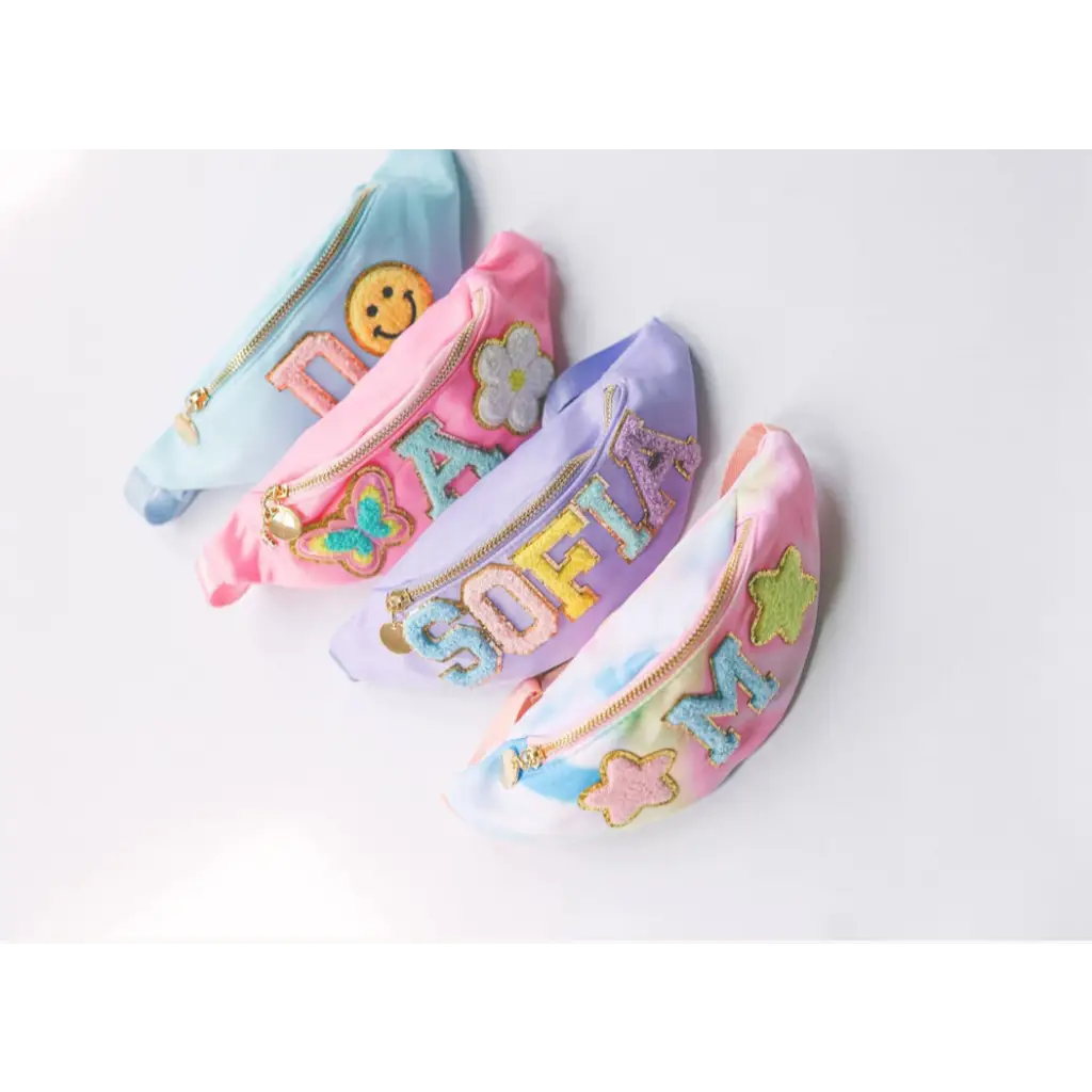 Four pastel-colored fanny packs with patches from the Design Your Own Bag Party Package at the craft bar