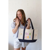 Cream canvas tote bag with navy bottom and colorful chenille patches for craft bar party