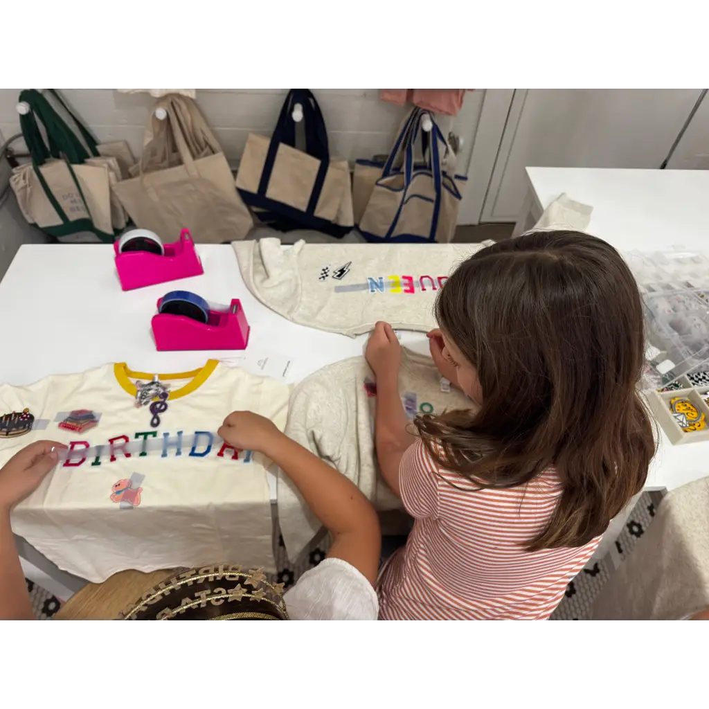 Kids decorating their shirts at the craft bar with fun letters and embellishments