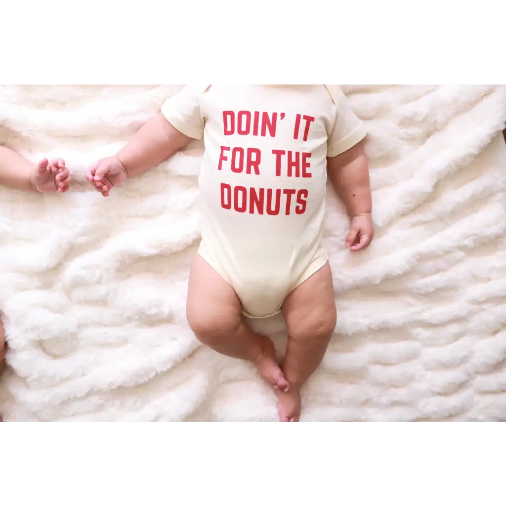 White baby onesie in organic cotton with red text saying DOIN IT FOR THE DONUTS