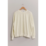 Cream-colored crew neck sweatshirt with drop shoulders hanging on a wooden hanger