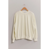 Cream-colored crew neck sweatshirt with drop shoulders hanging on a wooden hanger