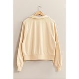 Cream-colored Eleanor Collared Raglan Sweatshirt hanging on a wooden hanger for stylish moms