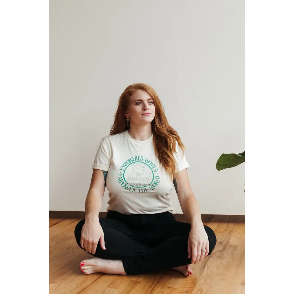 Person in a white Empowered Women Empower the World T-shirt by Polished Prints on wood floor