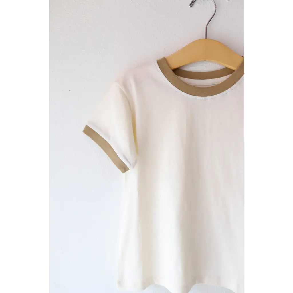 White Everyday Ringer Tee with tan trim hanging on a wooden hanger, perfect for casual style